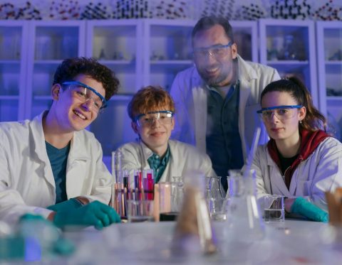 Schülerinnen und Schüler mit Schutzbrillen experimentieren gemeinsam im Chemielabor